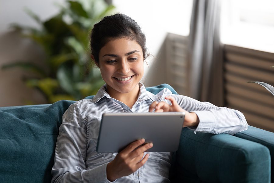 Client Center - Happy Woman Using Tablet on Sofa at Home